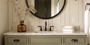 Modern bathroom vanity with a stone countertop, black faucet, and round mirror